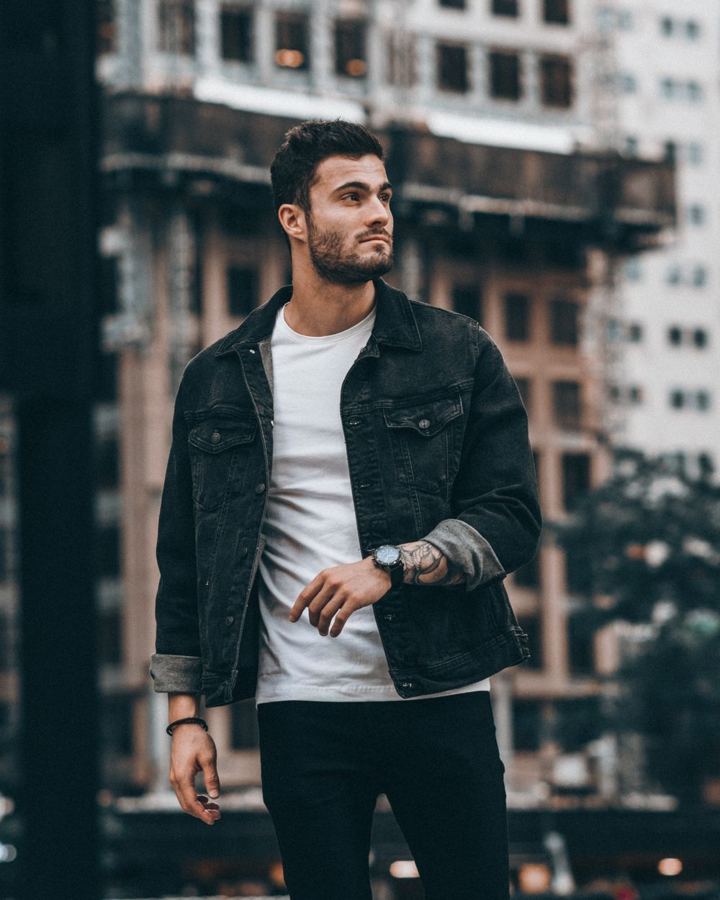 Man in a black jacket over a white tee at night